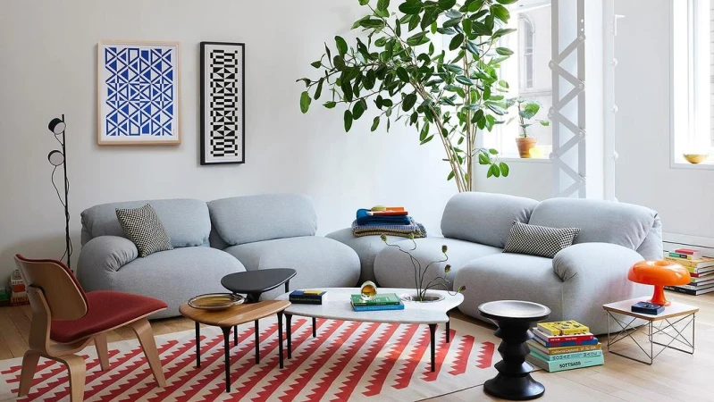 Living room interior featuring a grey sofa, patterned rug, and various decor elements, with a bright and airy ambiance.