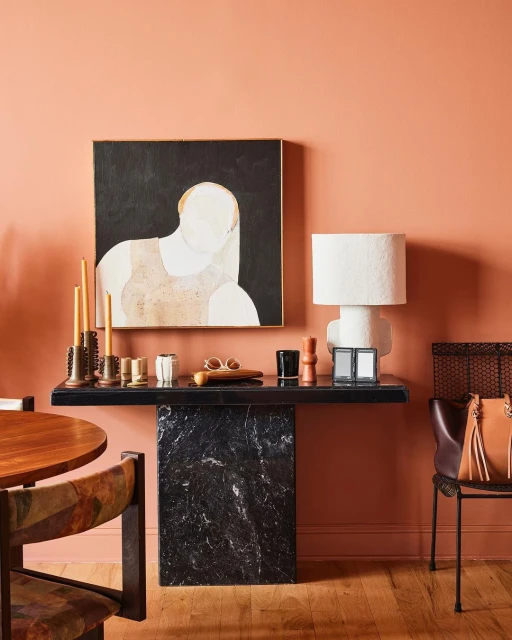 Modern interior design featuring abstract art, black marble console table, white ceramic lamp, and various decorative objects.