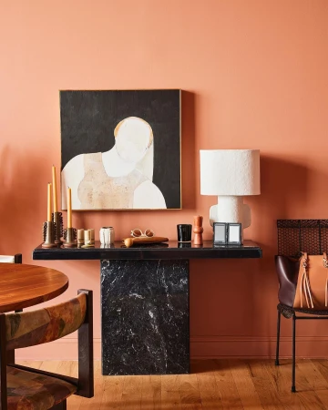 Modern interior design featuring abstract art, black marble console table, white ceramic lamp, and various decorative objects.