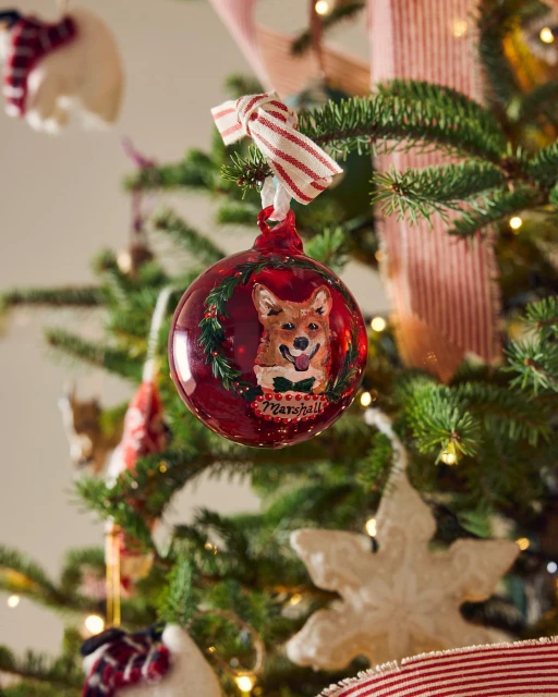 Festive Christmas tree ornament featuring a charming dog portrait surrounded by greenery and red ribbon, adding a personal touch.