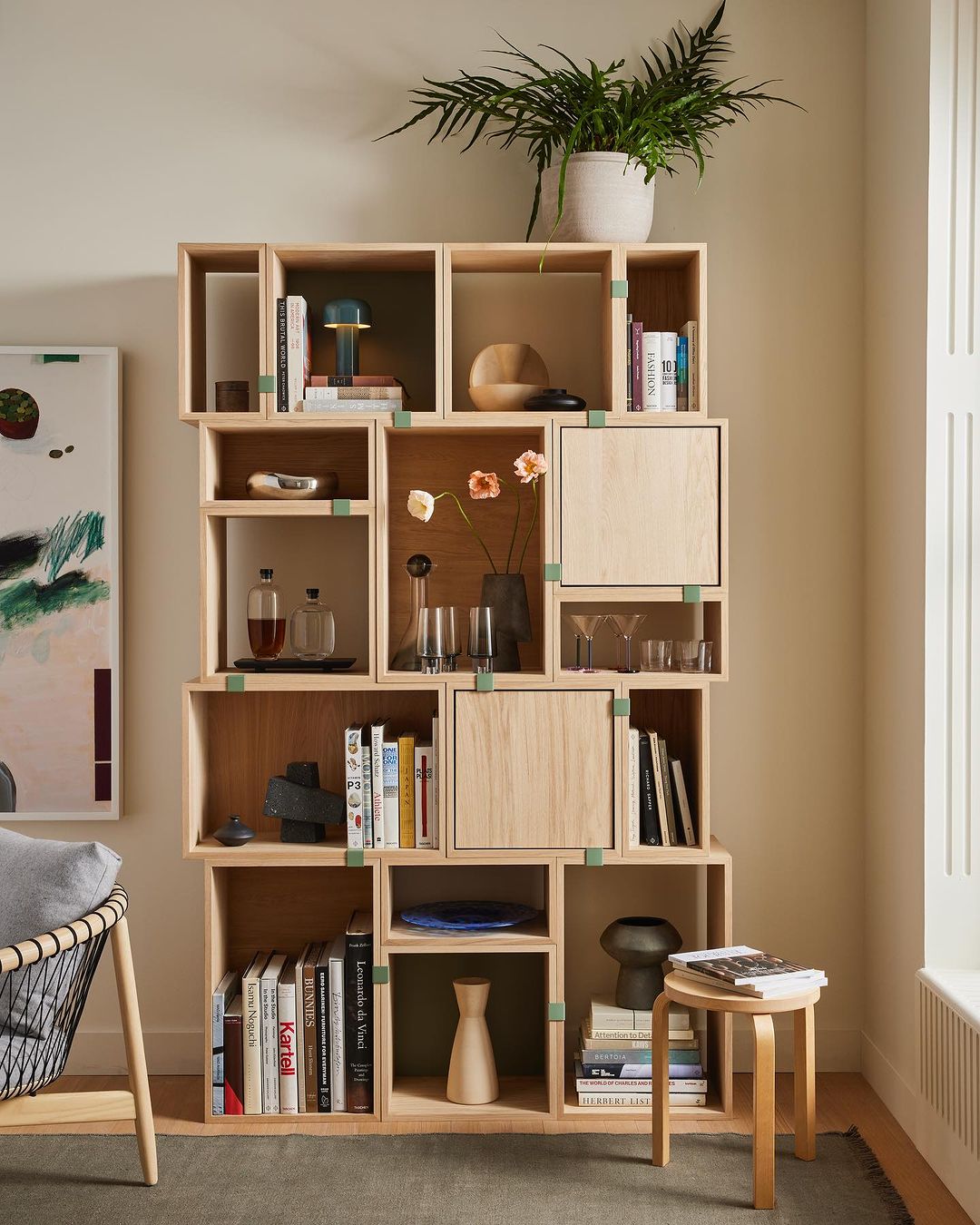 Stacked shelving unit with books, pottery, glassware, and decorative objects on display. Indoor home furnishing with Scandinavian design.