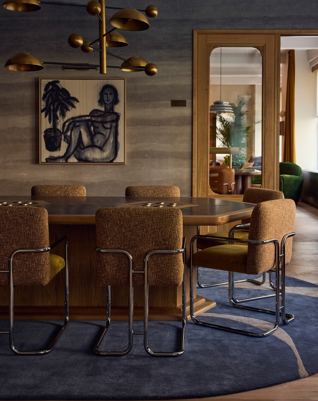 Dining room interior features a wooden table with upholstered chairs under a modern chandelier, complemented by a figure art piece.