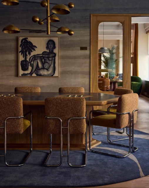 Dining room interior features a wooden table with upholstered chairs under a modern chandelier, complemented by a figure art piece.