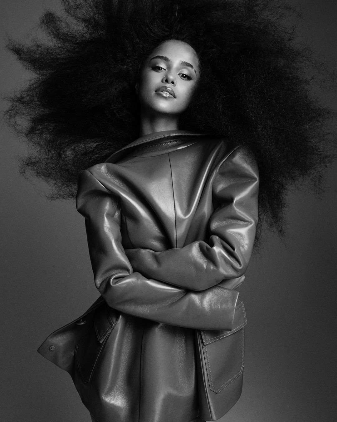 Monochrome portrait of a woman with voluminous afro hair wearing a leather jacket, photographed by Alvaro Beamud Cortes.