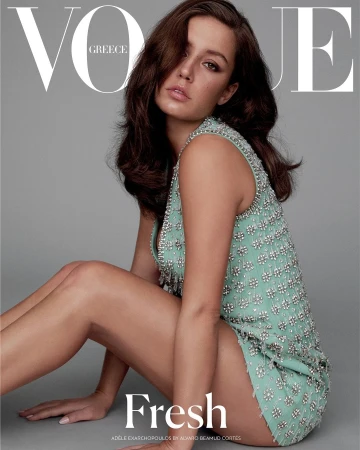 Adele Exarchopoulos crouching against a plain grey background wearing a mint green embellished sleeveless dress.