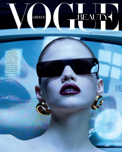 Vogue Greece Beauty cover featuring a model wearing oversized sunglasses, gold earrings, and dark lipstick with a blue backdrop.
