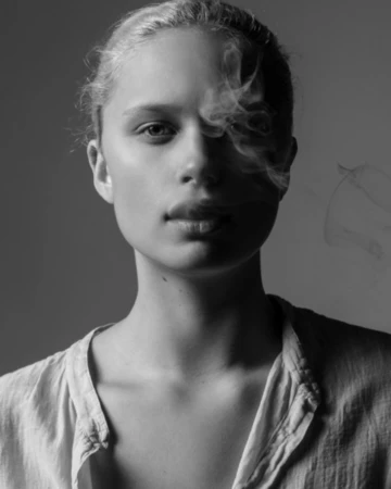 Monochrome portrait of a woman in a light top with wisps of smoke drifting across her face by photographer Amanda Demme