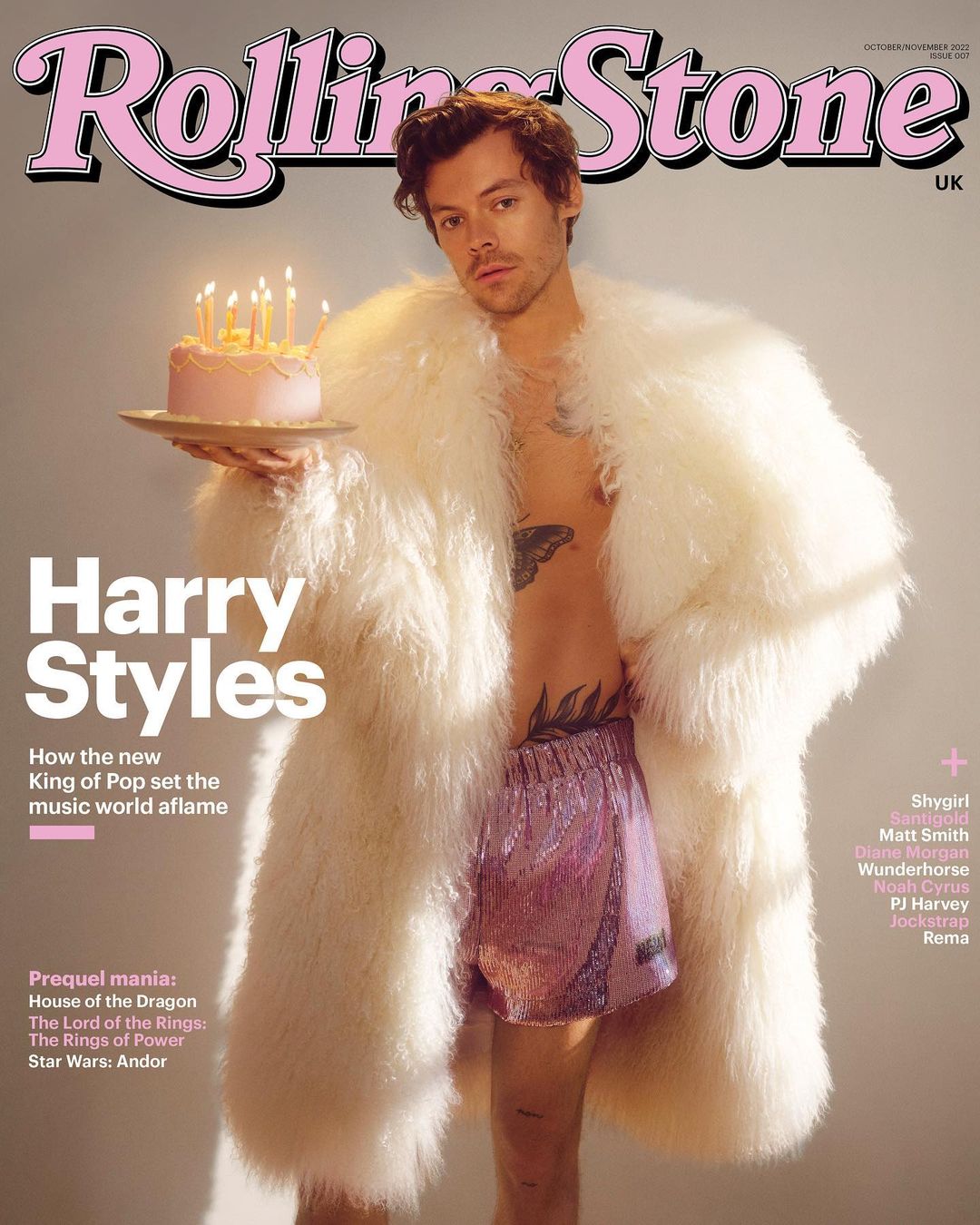 Rolling Stone cover featuring Harry Styles holding cake in white coat and pink shorts with tattoos. The cover has pink and white retro design.