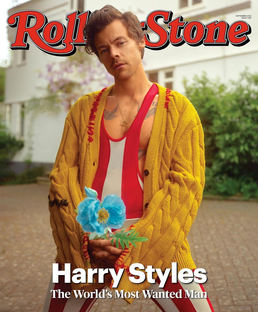 Harry Styles on Rolling Stone cover in yellow cardigan and striped top, holding a blue flower against an outdoor setting.