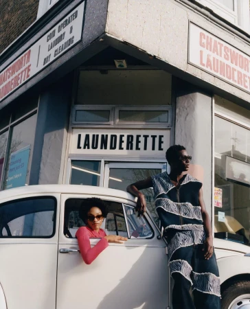 Two models posing with a vintage white car in front of a London launderette by photographer Amber Pinkerton.