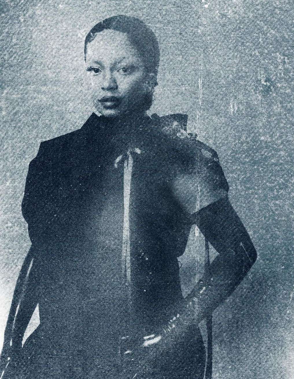 An adult female in a dark dress with a high collar and satin ribbons, captured in a close-up shot with a textured, vintage-style backdrop.