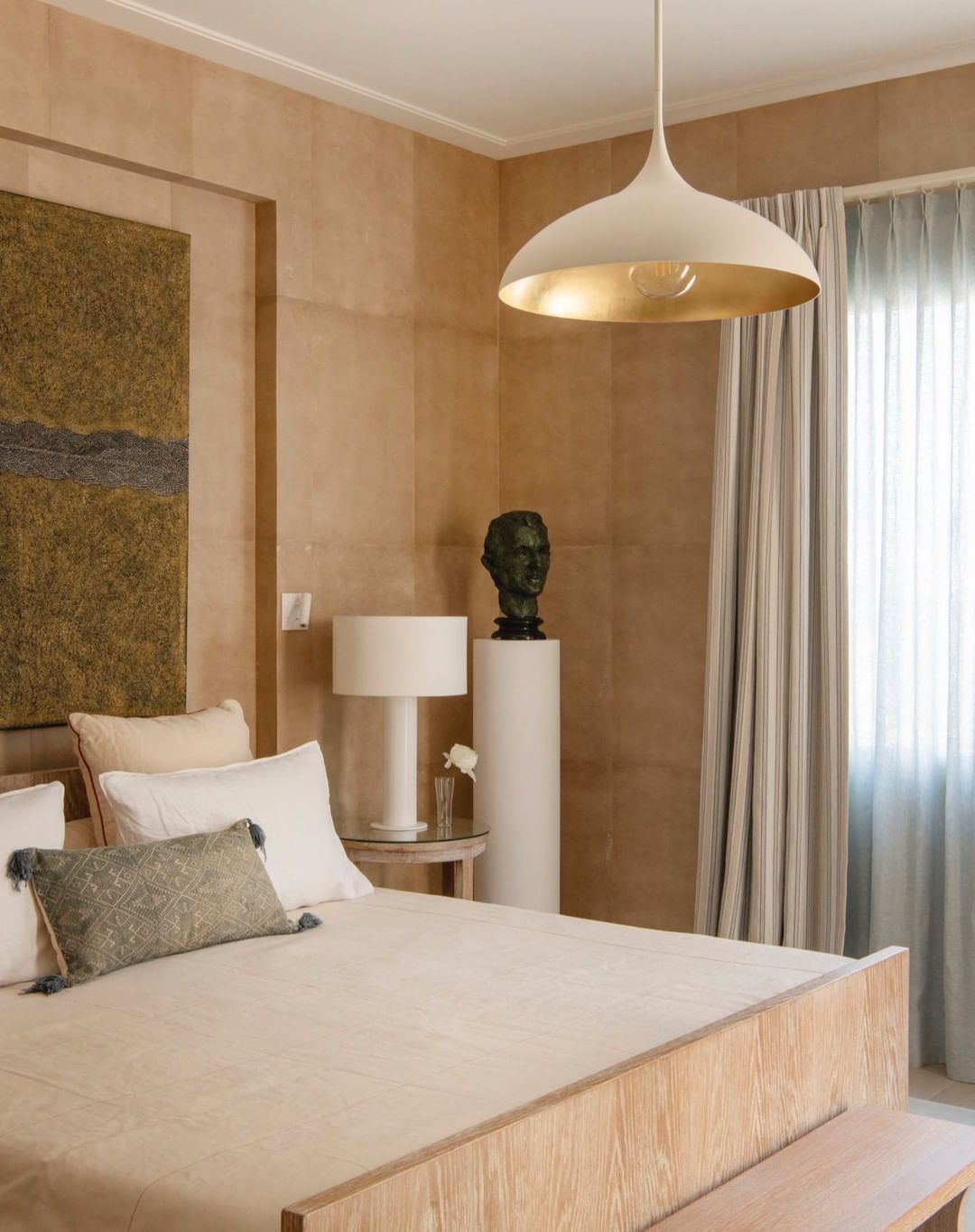 Bedroom interior with a wooden bed, neutral color palette, beige walls, and a modern pendant light fixture, creating a calm and inviting space.