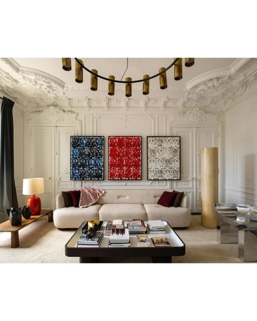 Living room features a neutral sofa, dark wood coffee table with books, colorful abstract art, and a striking modern chandelier.