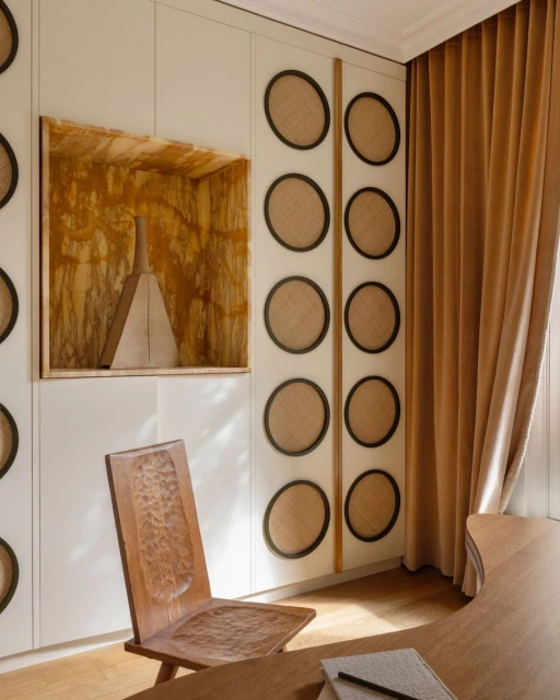 Interior space with a wooden chair, decorative wall, and neutral-toned curtains, showcasing a blend of textures and minimalist design.