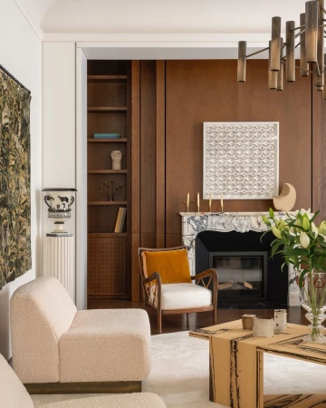 Living room interior featuring modern seating, marble fireplace, and decorative wall art, creating a stylish and cozy home environment.