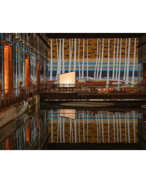 Interior view of The Turbine Hall at Tate Modern museum in London with a reflective pool and an art installation backdrop.
