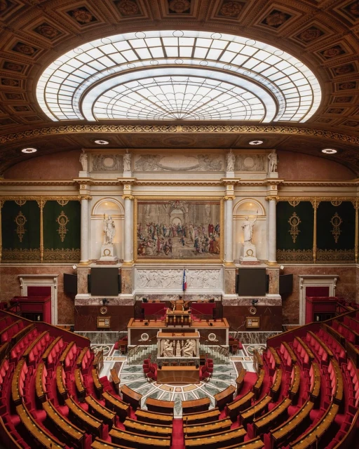Elaborate view inside a government building's legislative chamber featuring rows of seating and a speaker's podium.