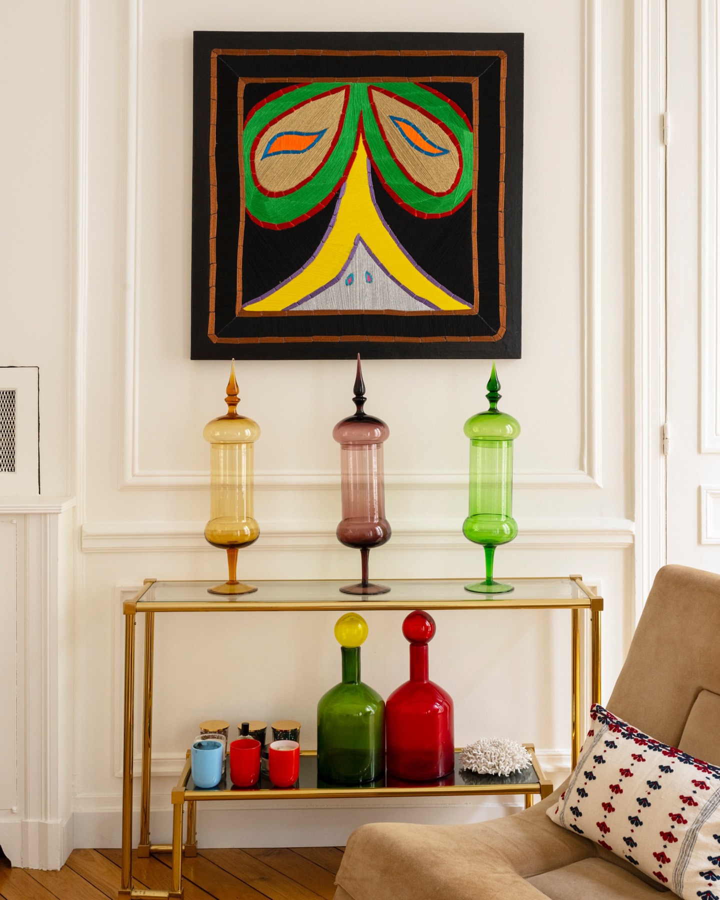 Interior with console table holding glassware, decorative objects, and graphic art on the wall in a bright and modern living space.