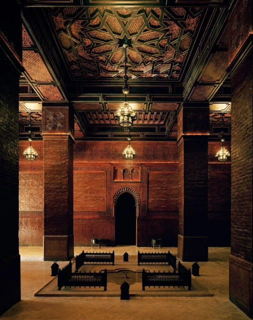 Elaborate interior architecture featuring a geometric patterned ceiling, arched doorway, and dark brown columns in a spacious room.