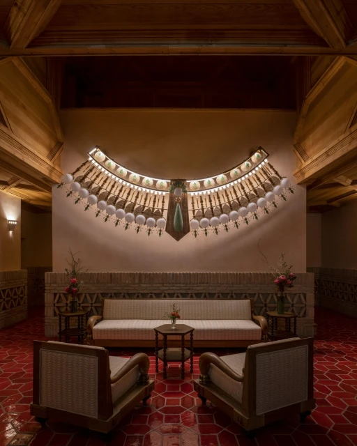 Elegant interior featuring a cream sofa flanked by rattan chairs, set against a decorated wall with Egyptian-style art and warm lighting.