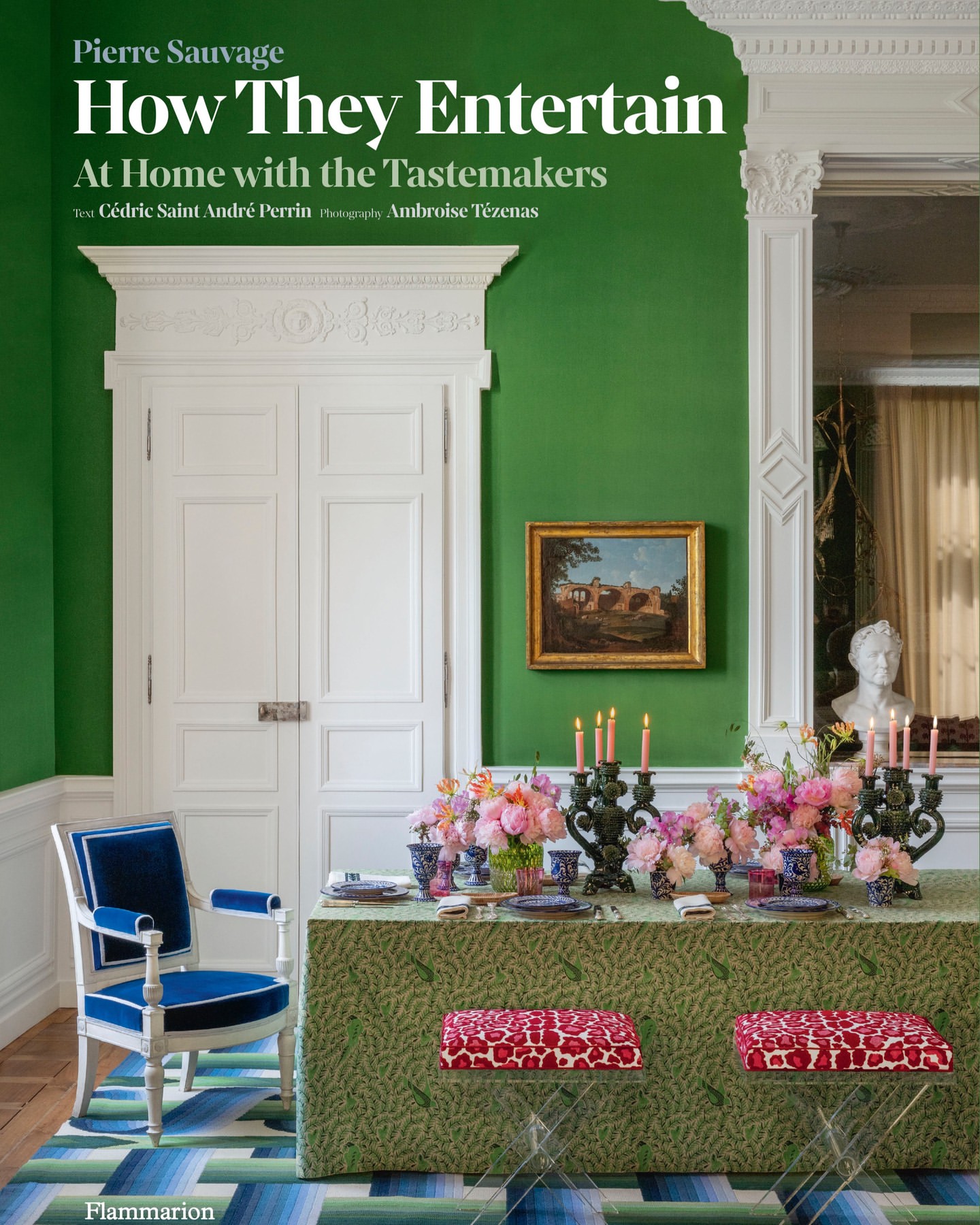 Interior of a dining room with green walls, white trim, and a table set with flowers, candles, and dishes, beside a white and blue chair.