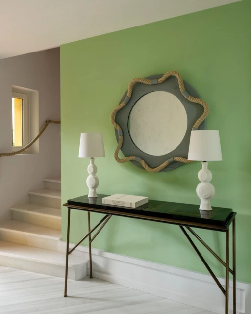 Interior view of a hallway with a console table, two lamps, and a decorative mirror, showcasing minimalist design elements and soft lighting.