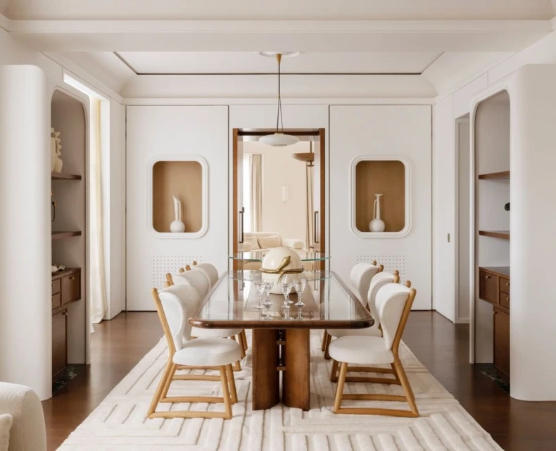 Modern dining room interior with wood table, white chairs, and geometric rug, illuminated by a pendant light fixture.