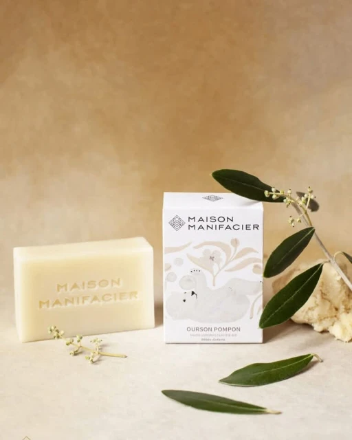Artisanal bar soap and product packaging on neutral background with olive leaves, studio shot for the beauty and personal care industry.
