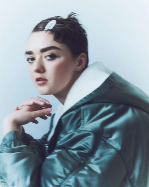 Stylish woman with short brown hair, wearing a glossy green puffer jacket and white collared shirt in a studio portrait.