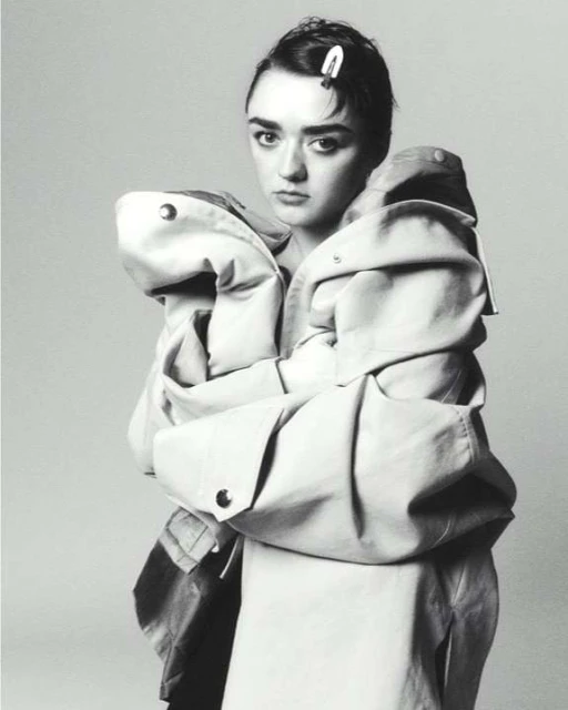 Monochrome portrait of a young woman wearing an oversized coat with an unhappy expression, and a barrette in her hair.