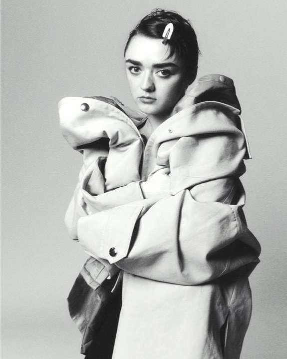 Black and white portrait of Maisie Williams wearing an oversized coat with a hair clip, photographed in Paris.