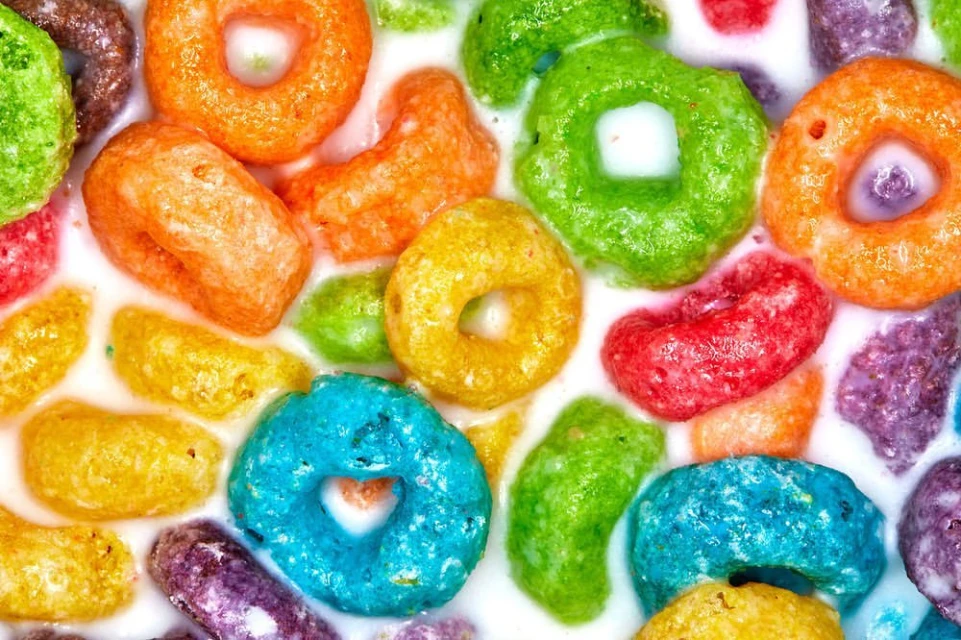 Close-up of colorful frosted cereal loops floating in a bowl of white milk, filling the frame in a visually appealing way.