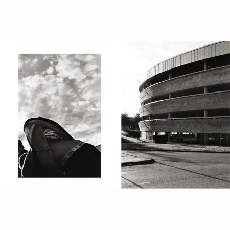 Monochrome photo showcasing a hooded jacket against a cloudy sky and an architectural parking structure against a street.