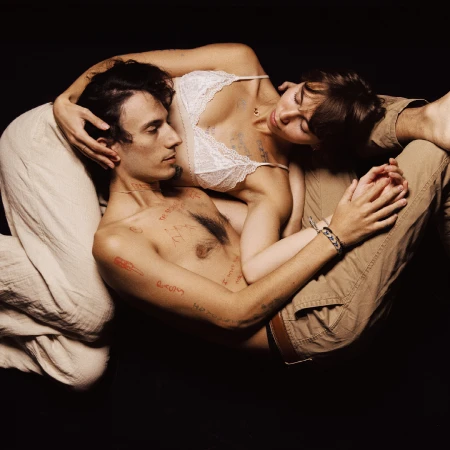 Close-up portrait of a couple embracing intimately against a dark background, photographed by Anais Stupka in London.