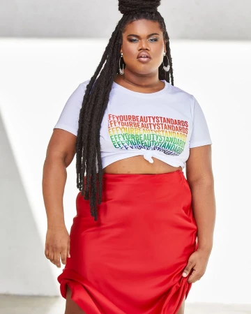 Plus size woman in white t-shirt with rainbow graphic text and red satin skirt against a seamless background