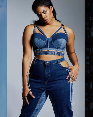 Model wearing a blue denim crop top and matching jeans with side cutouts against a studio backdrop