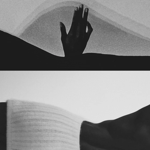 Monochromatic studio shot of a hand reaching up, contrasted with fabric detail and black abstract shapes. Graphic, high-contrast aesthetic.