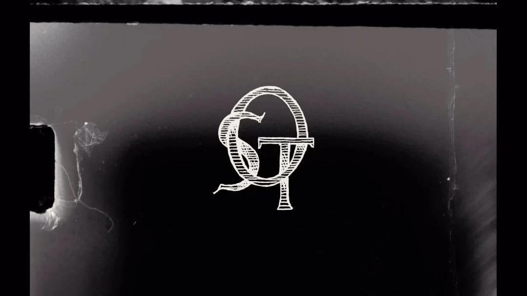 Monochromatic background with a white monogram featuring intertwined letters G and T, presented in a stylized and vintage design.