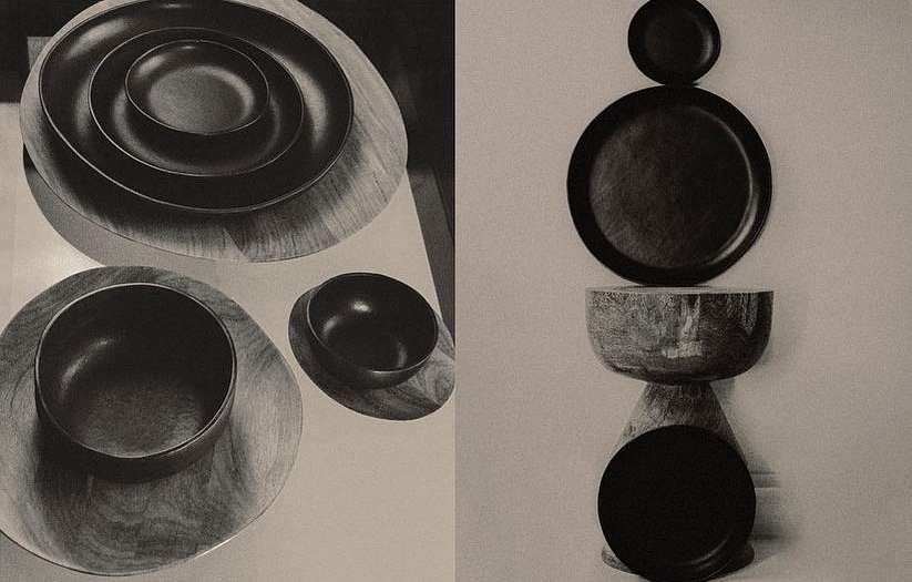 A collection of dark bowls and plates made of wood, arranged in a visually striking composition with a minimalist and contemporary aesthetic.
