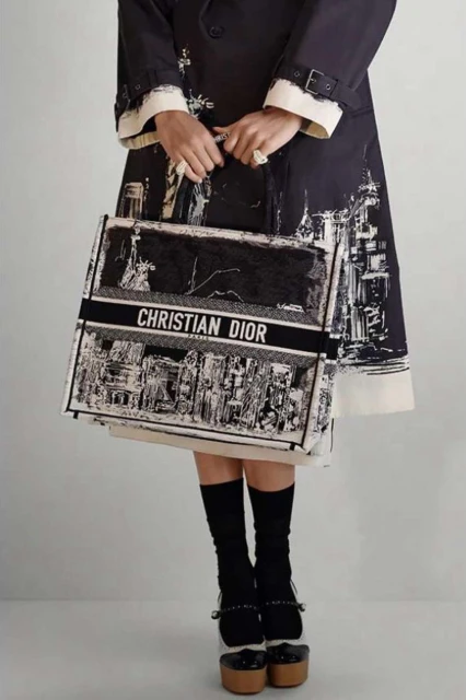 Fashion shot: Woman with Christian Dior tote bag, wearing black and white coat, knee socks, and platform heels in studio.