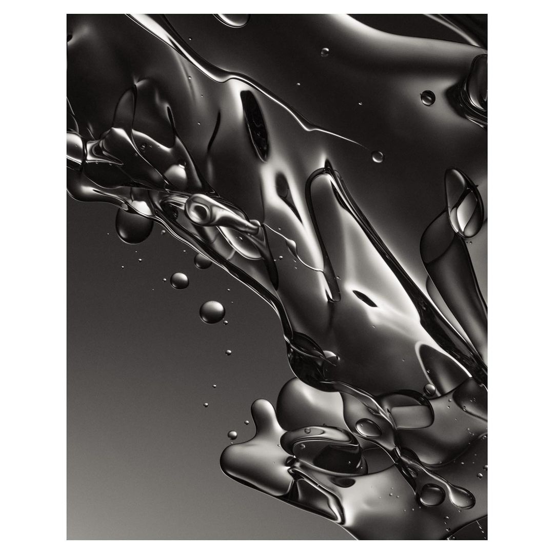 Abstract close-up image of clear liquid with light and shadows creating various shades of gray, smooth textures, and small air bubbles.