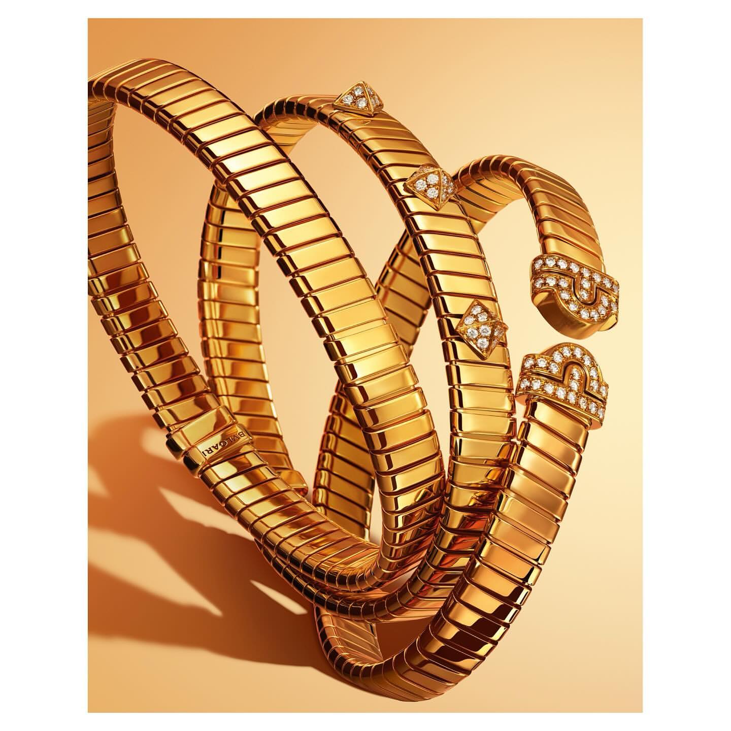 Close-up studio shot showcasing a gleaming gold bracelet, its metallic links and diamond accents catching the light on a yellow gradient background.