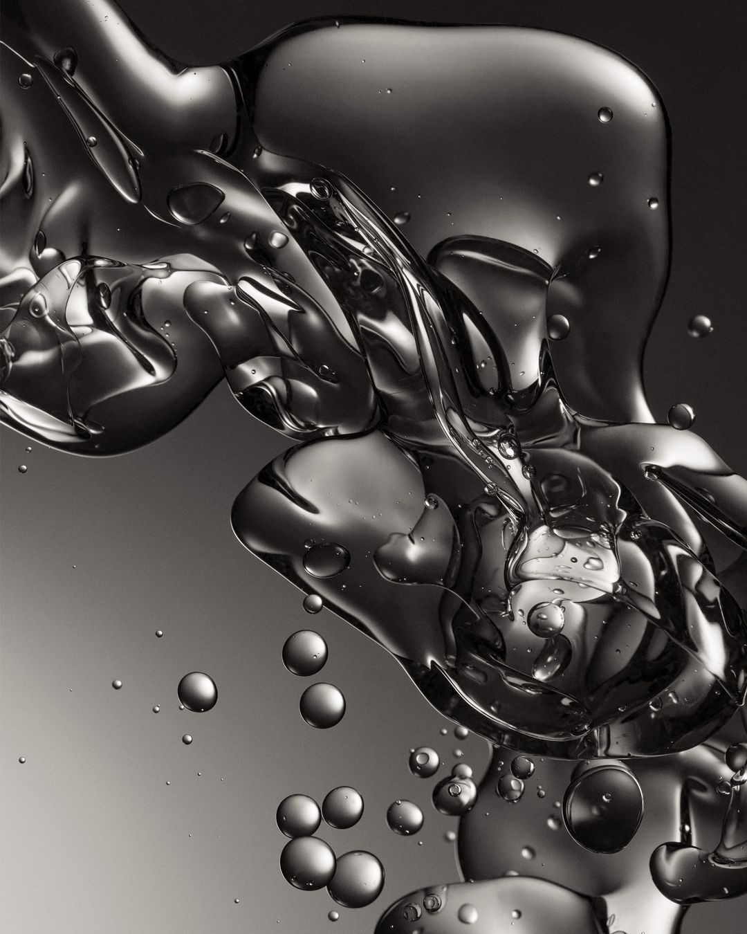 Abstract still life of oil and water creating liquid spheres and abstract shapes against a graduated grey background, macro photography.