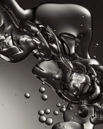 Abstract still life of oil and water creating liquid spheres and abstract shapes against a graduated grey background, macro photography.