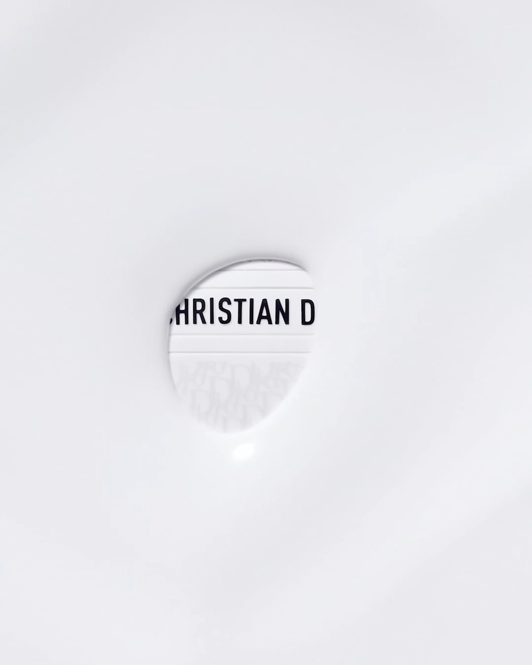 Close-up of a lightbox displaying the text 'CHRISTIAN D' against a white background, minimalist aesthetic.