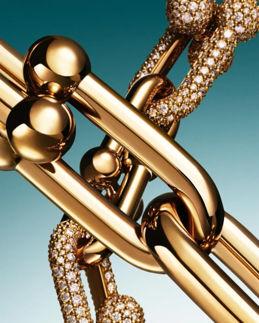 Close-up of interlocking gold chain-link Tiffany bracelets, some with diamond embellishments, against a teal background.