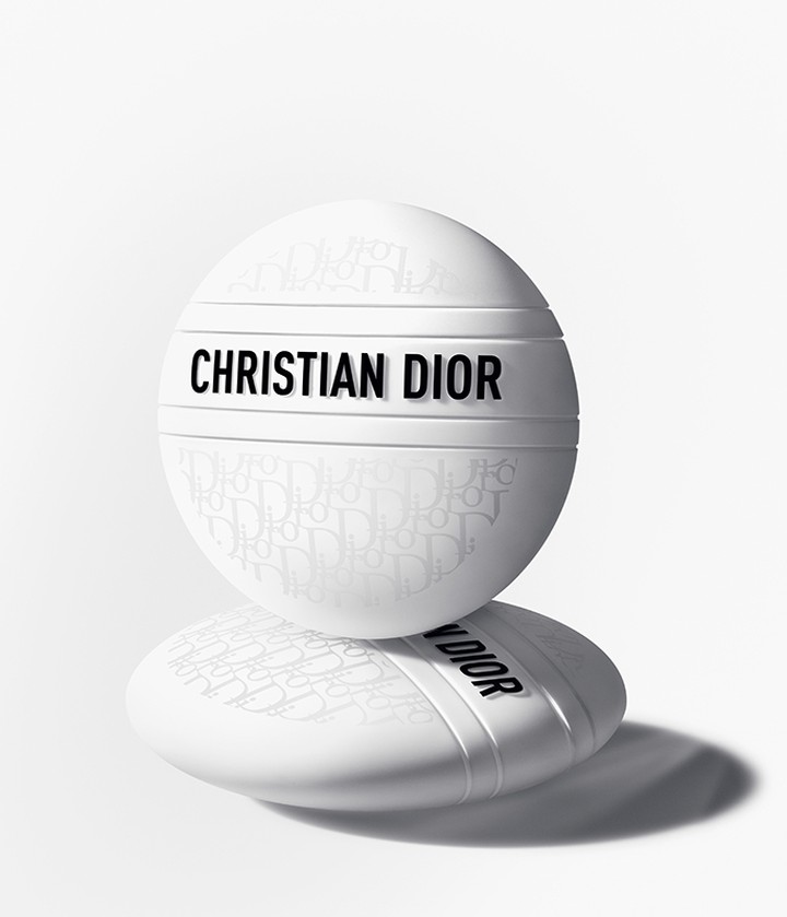 Two white Christian Dior skincare containers stacked on each other against a bright white background with a shadow beneath. Beauty shot.