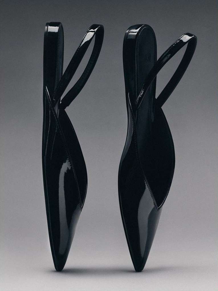 Elegant black slingback shoes with pointed toes and slender straps arranged on a neutral grey backdrop for a minimalist fashion statement.