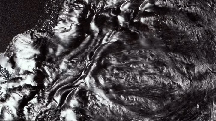 Abstract monochrome pattern of liquid or flowing material in black and white tones creating an artistic and textured surface.