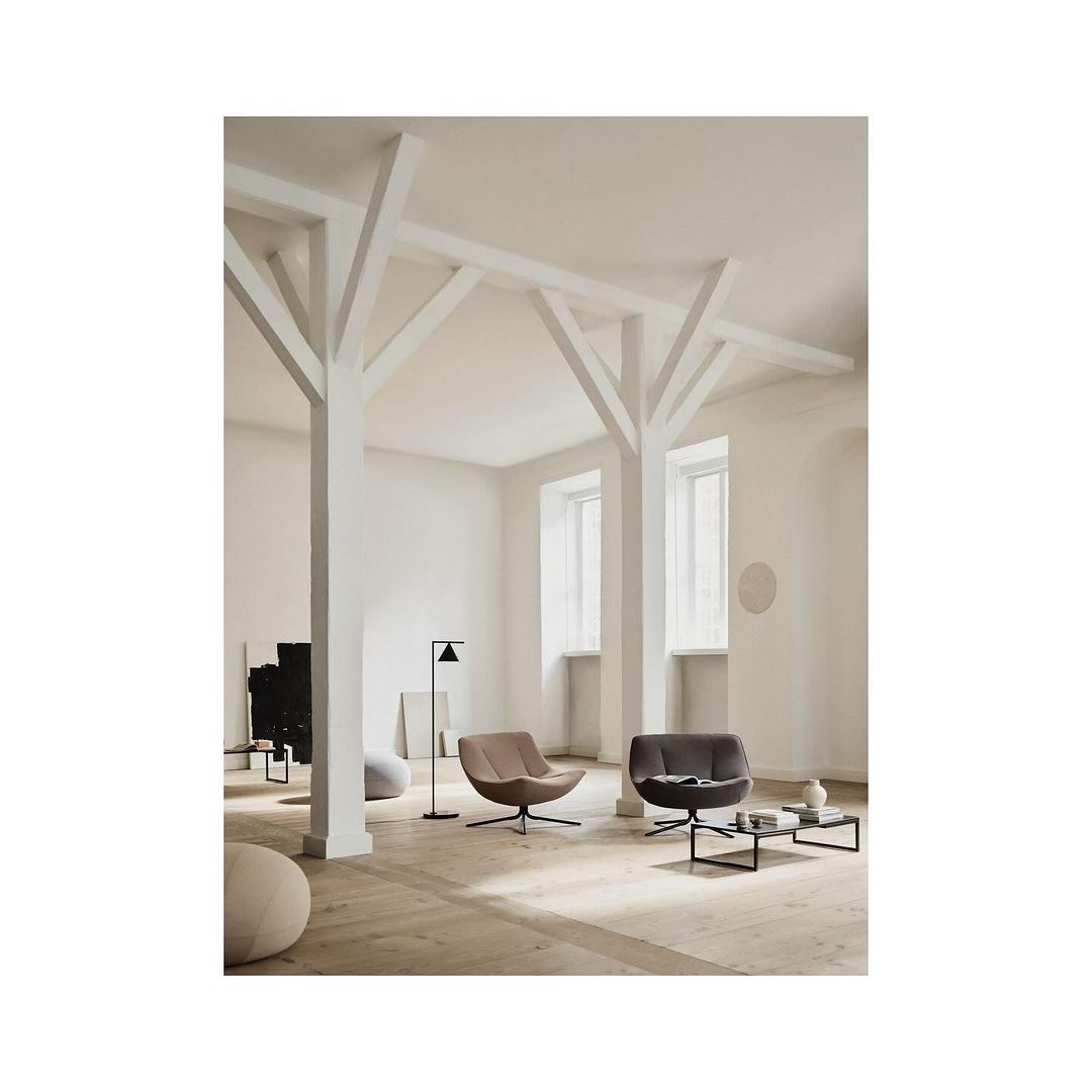 Interior design with two modern swivel armchairs, black coffee table, and floor lamp in a bright, minimalist setting with wood floors.